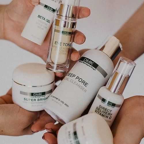 Skincare products held in hands, including cleansers and vitamin C serum.